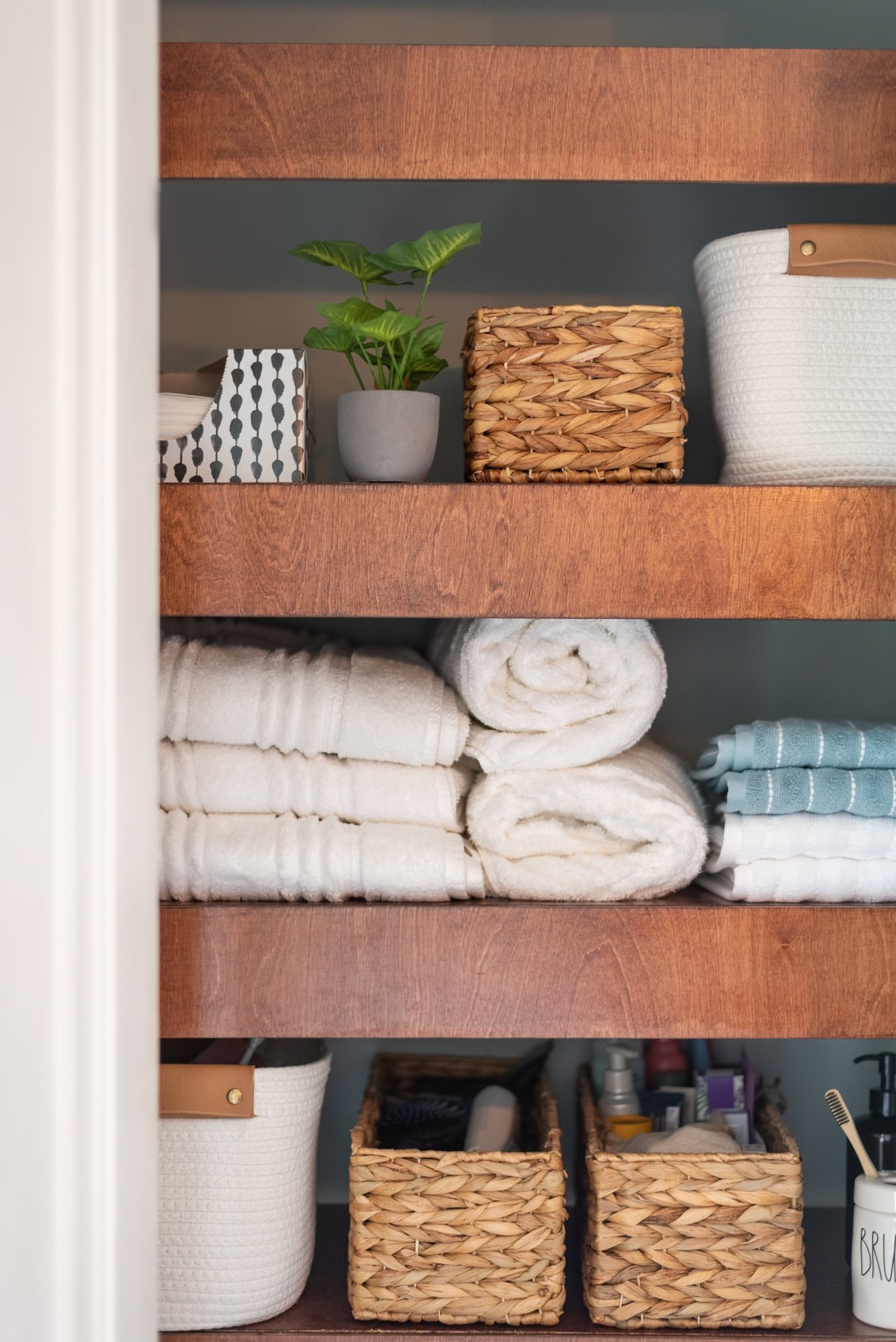 Neatly organized bathroom closet with stylish wooden shelves and baskets